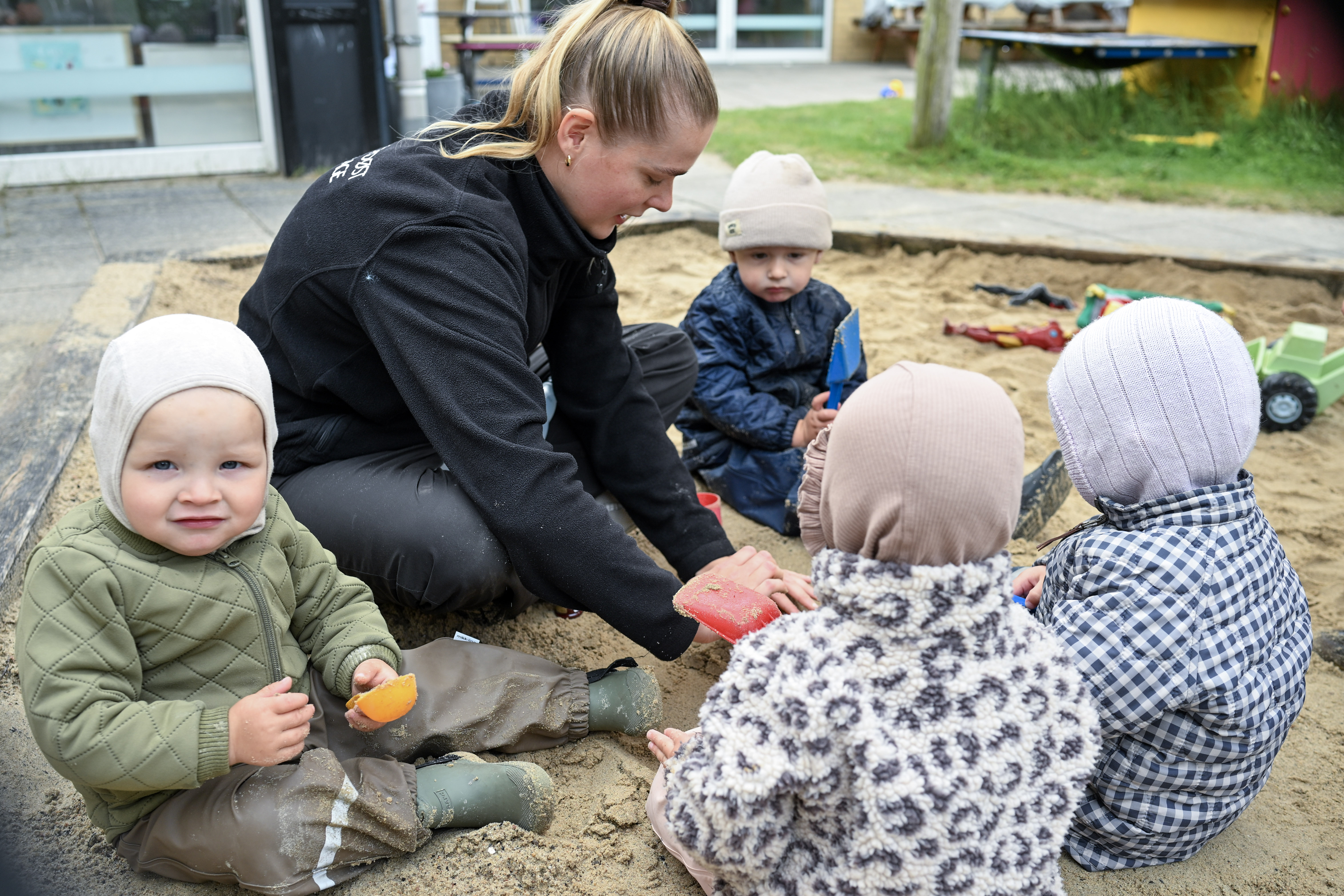 Voksen leger med børn i sandkasse