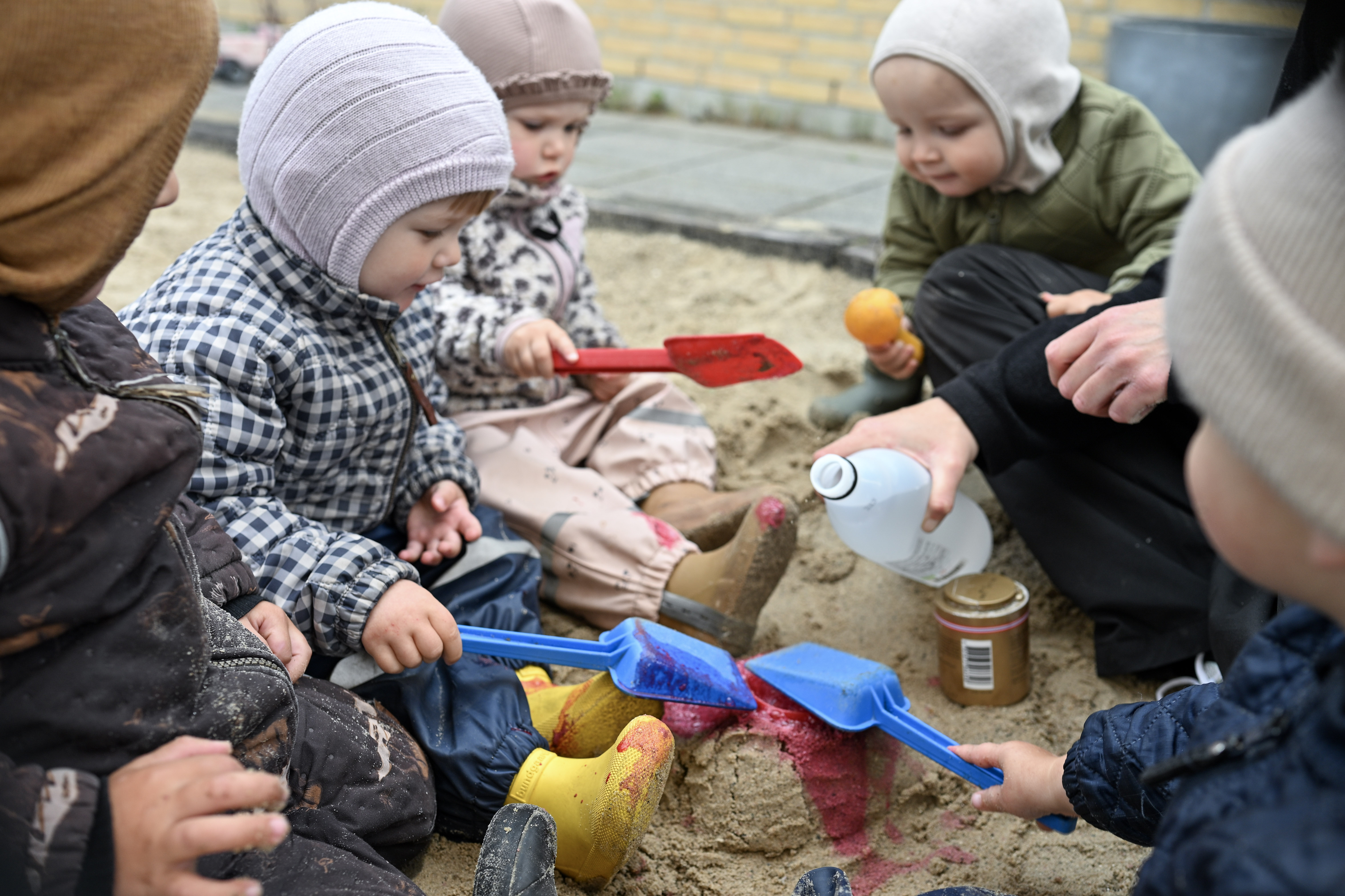 Voksen leger med børn i sandkasse