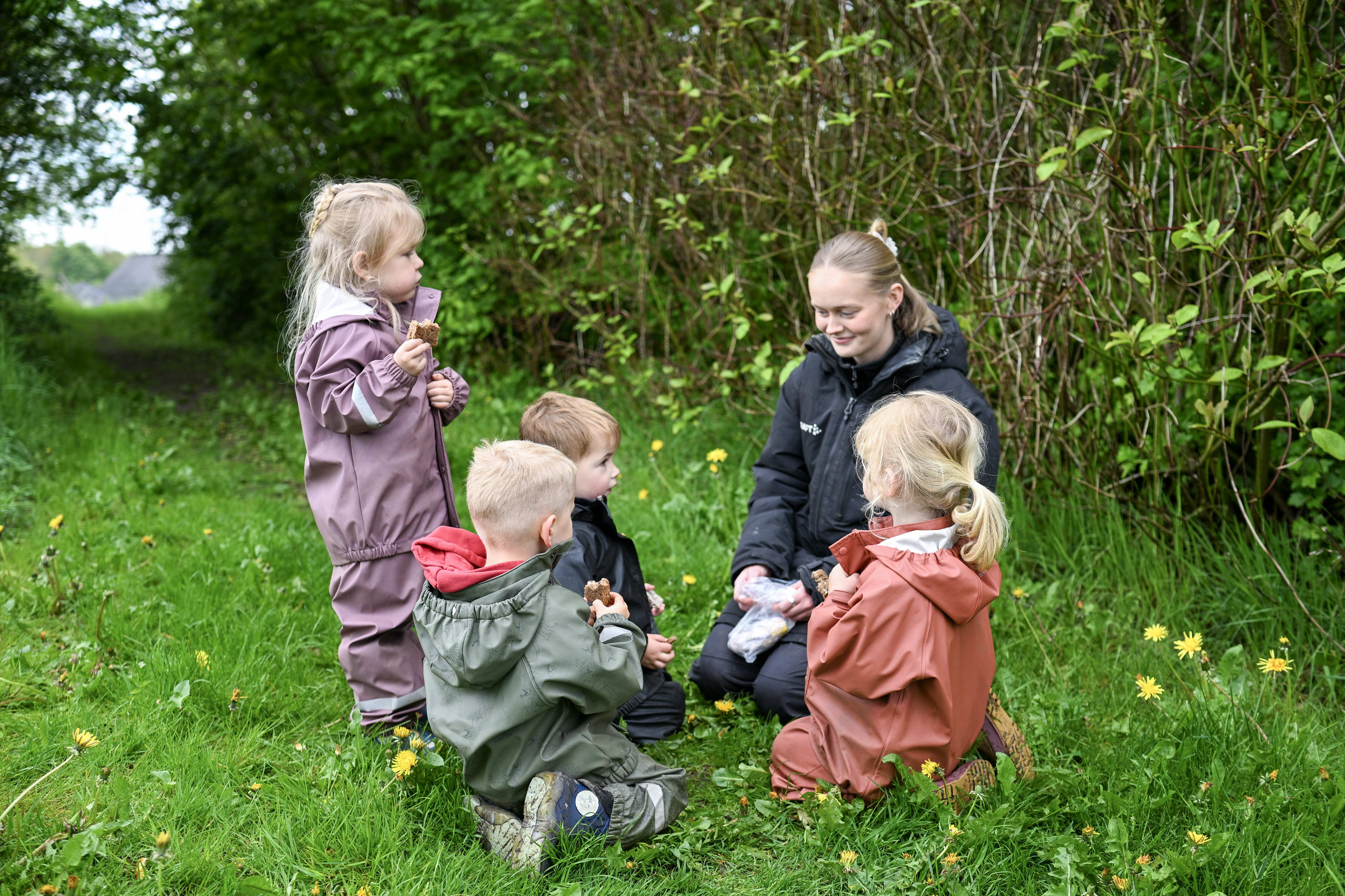 Voksen og fire børn spiser i naturen