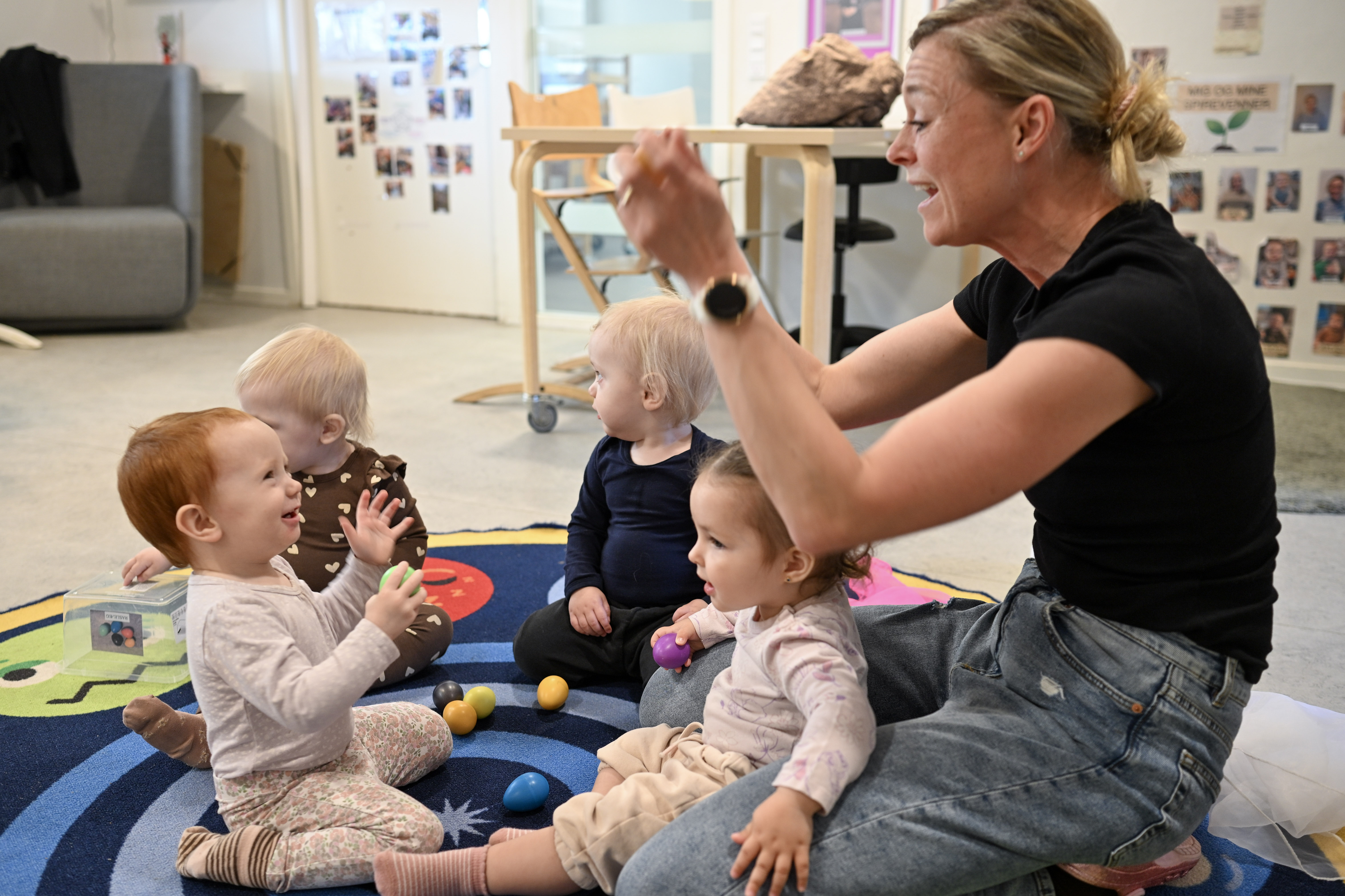 Voksen leger med børn på tæppe